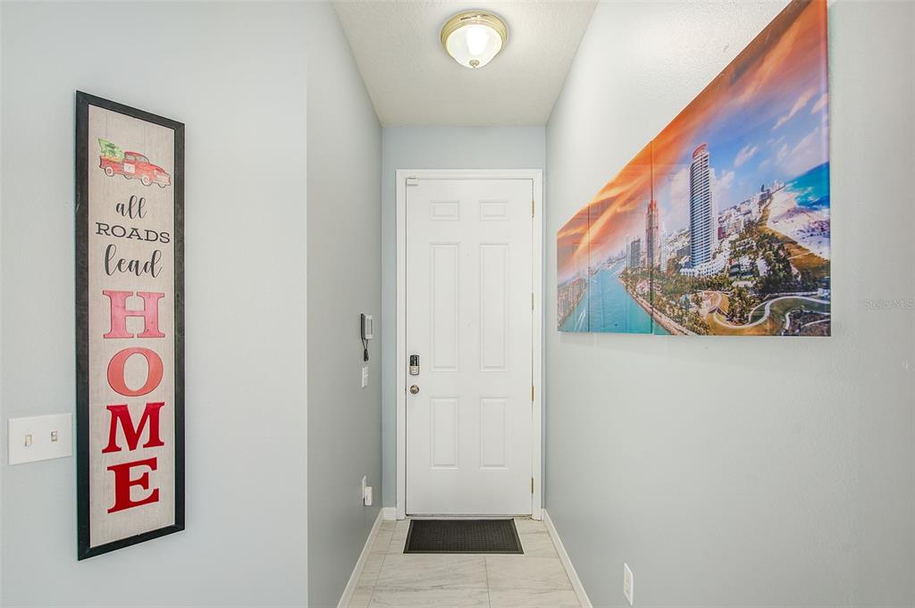 An entryway features a white front door, light-colored tile flooring, and wall art — 12136 TREE HAVEN AVENUE, GIBSONTON, FL