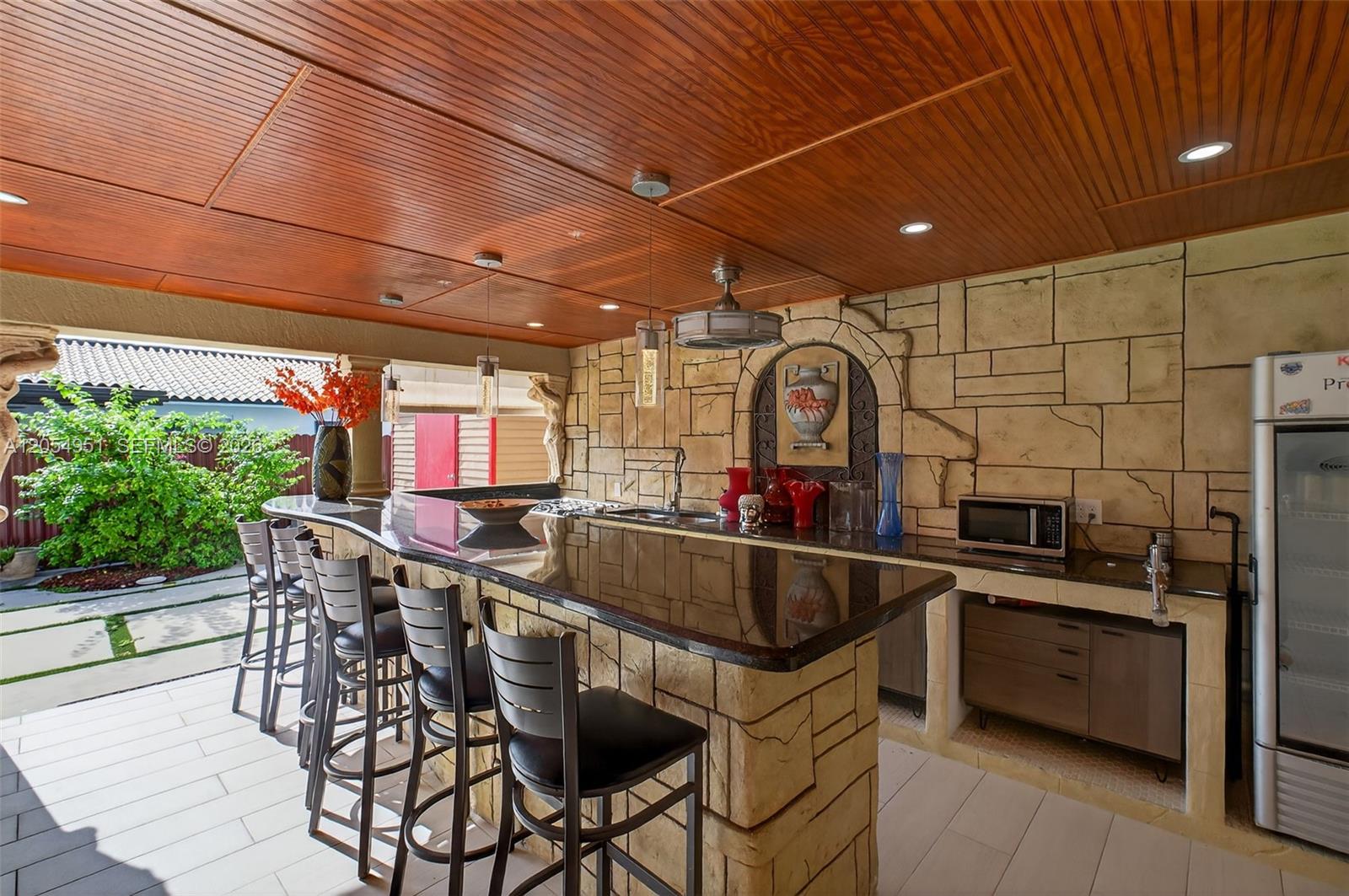 An outdoor kitchen features a stone bar, wood-paneled ceiling, and stainless steel appliances — 2431 SW 127th Ave # 2431, Miami FL 33175, MIAMI, FL