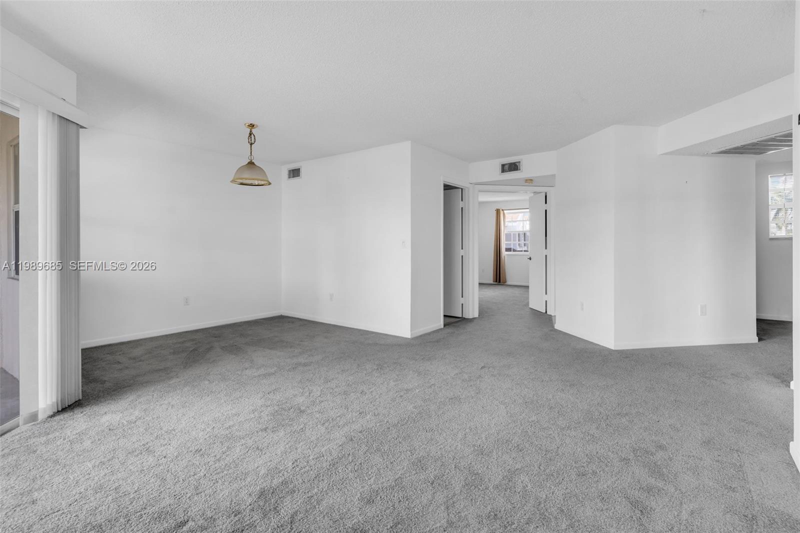 An empty room with gray carpeting, white walls, and a hanging pendant light fixture — 2274 SE 27th Dr # F, Homestead FL 33035, HOMESTEAD, FL