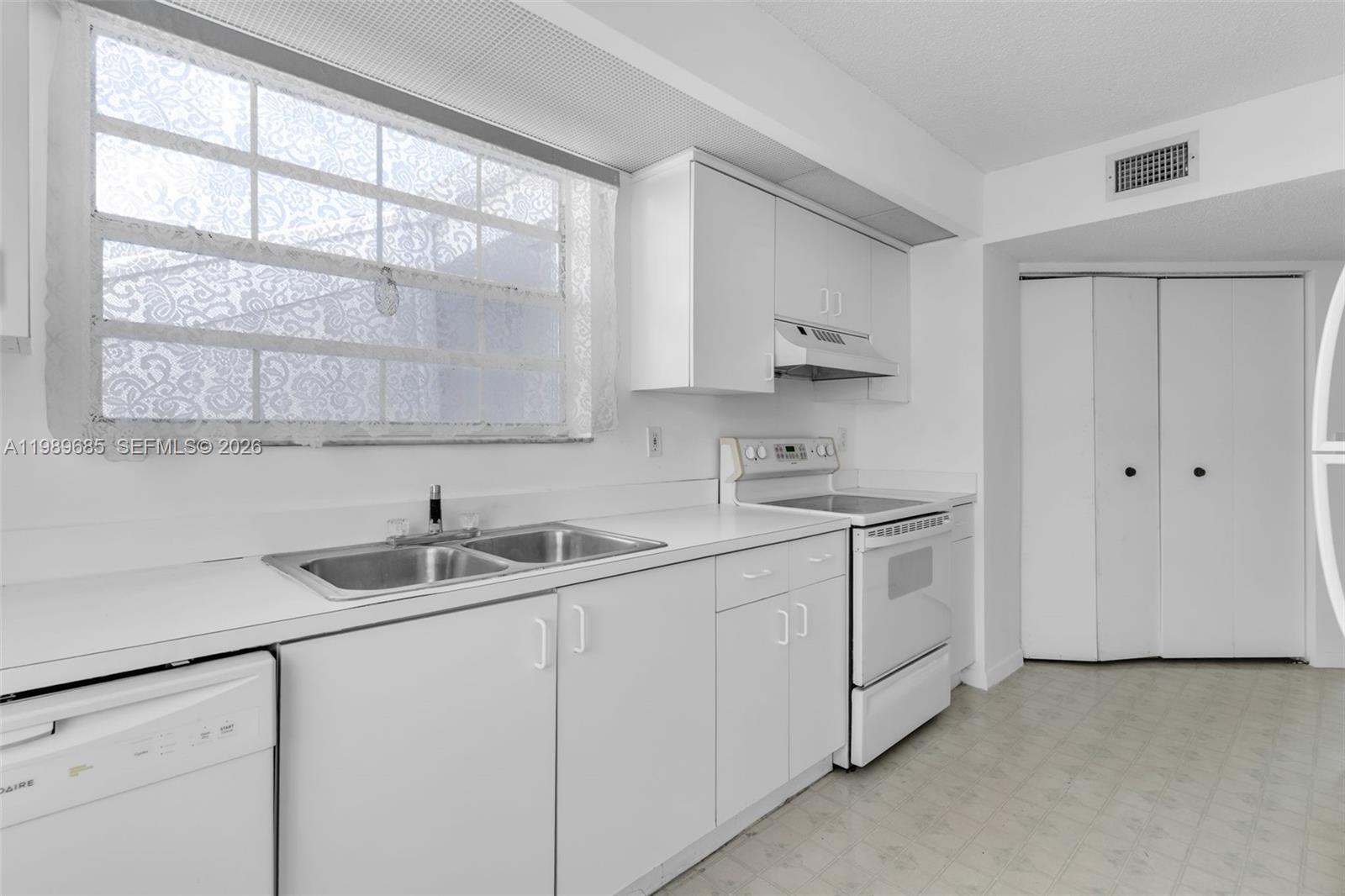 A kitchen features white cabinets, a double sink, and white appliances against a white wall — 2274 SE 27th Dr # F, Homestead FL 33035, HOMESTEAD, FL