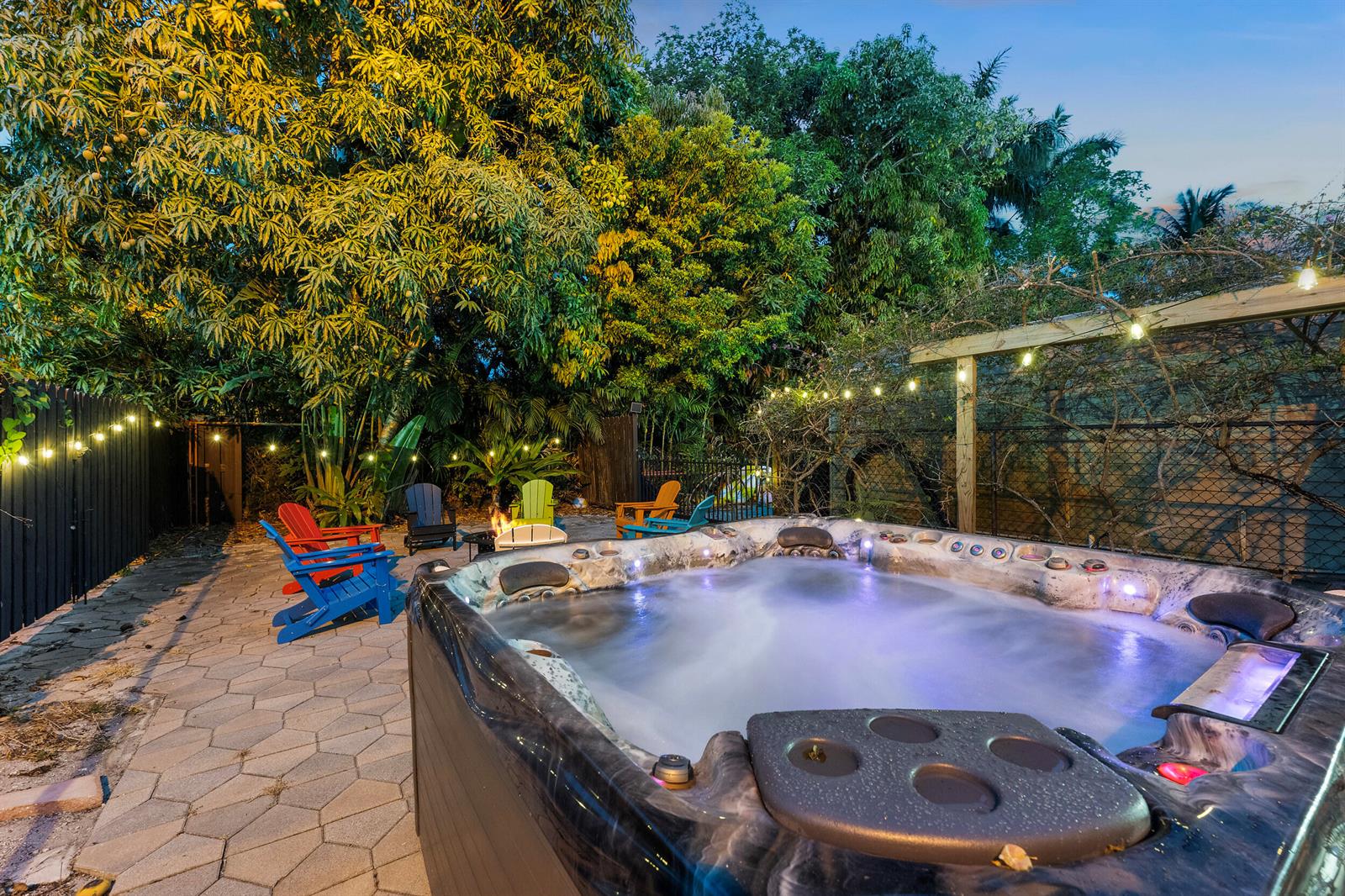 A hot tub sits on a paved patio with colorful Adirondack chairs and string lights — 643 36th Street, West Palm Beach FL 33407, WEST PALM BEACH, FL