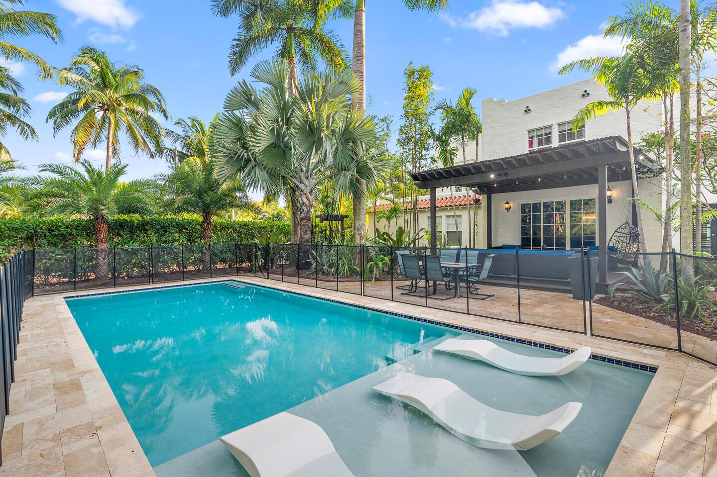 A swimming pool with a tanning ledge and lounge chairs sits beside a covered patio — 643 36th Street, West Palm Beach FL 33407, WEST PALM BEACH, FL