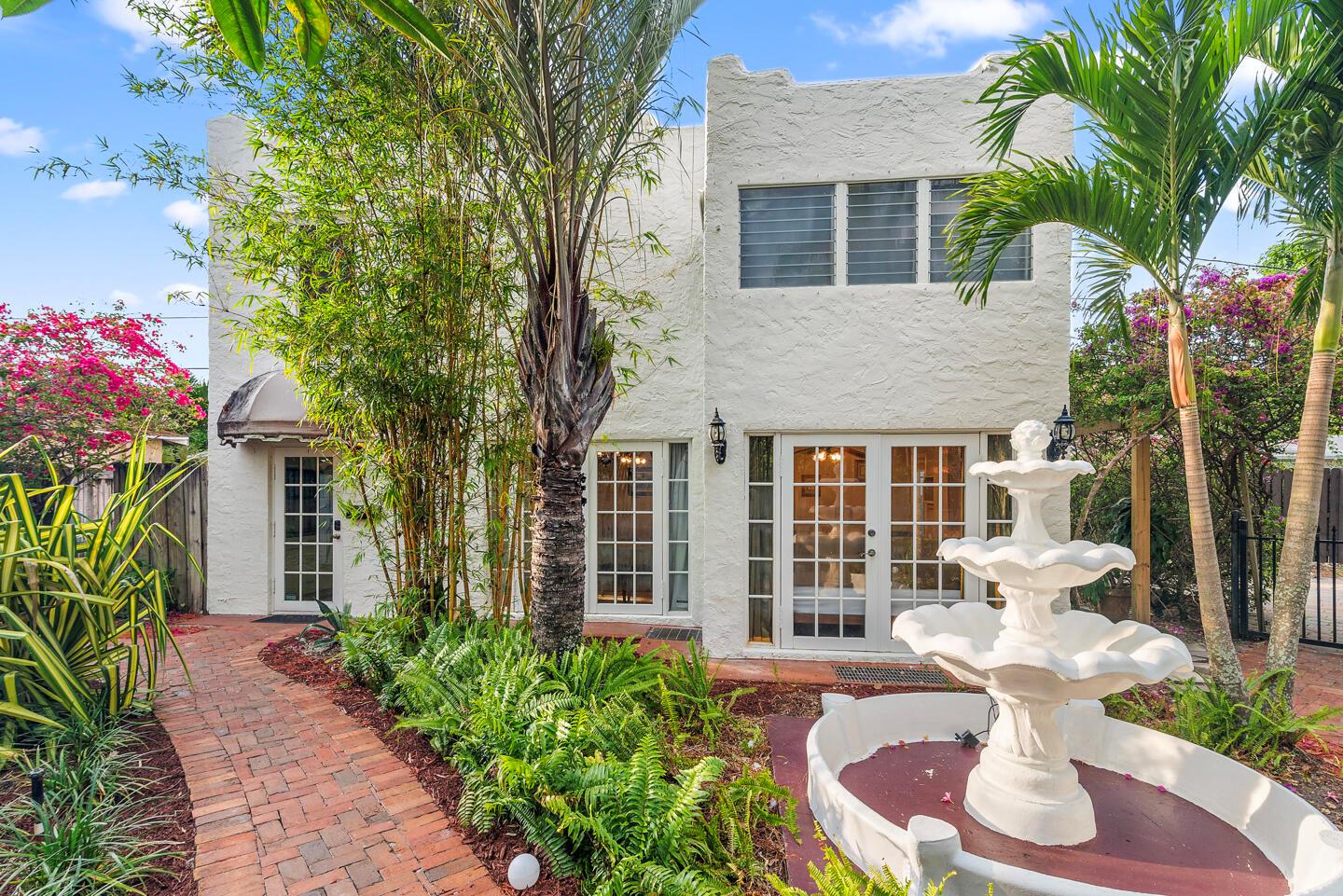 A white two-story stucco building with a brick walkway, tropical landscaping, and a tiered fountain — 643 36th Street, West Palm Beach FL 33407, WEST PALM BEACH, FL