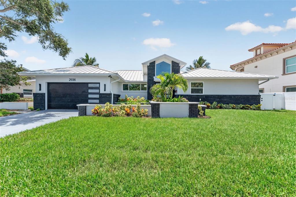 A single-story house with a metal roof, dark brick accents, and a front lawn — 2936 68TH AVENUE S, ST PETERSBURG, FL