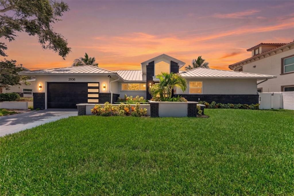 A single-story house with a metal roof, black brick accents, and a manicured front lawn — 2936 68TH AVENUE S, ST PETERSBURG, FL