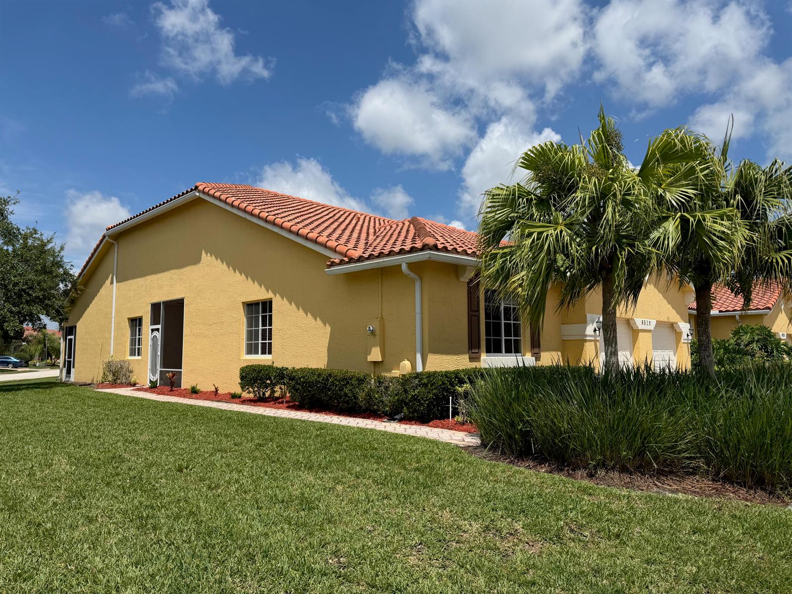A yellow single-story house with a red tile roof and palm trees in the front yard — 6510 Oxford Circle # 101, Vero Beach FL 32966, VERO BEACH, FL