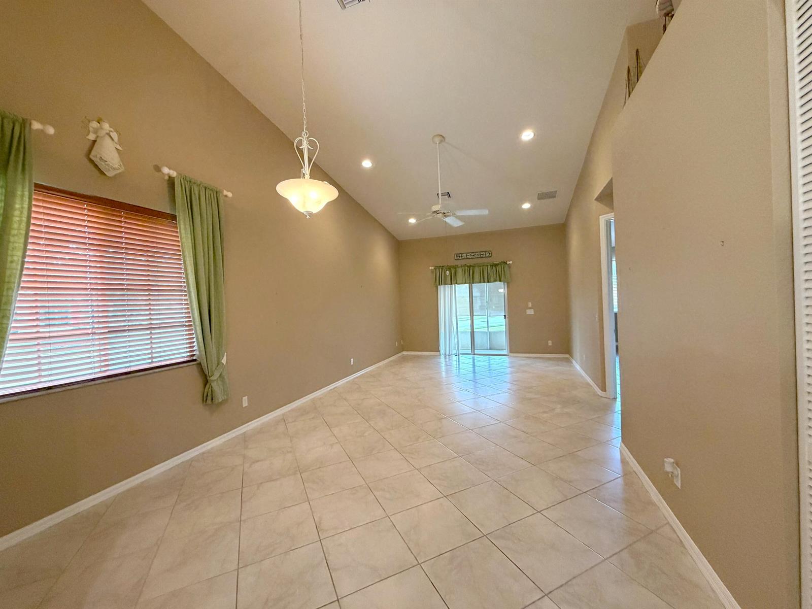 An empty room with beige walls, tile flooring, a ceiling fan, and a hanging light fixture — 6510 Oxford Circle # 101, Vero Beach FL 32966, VERO BEACH, FL