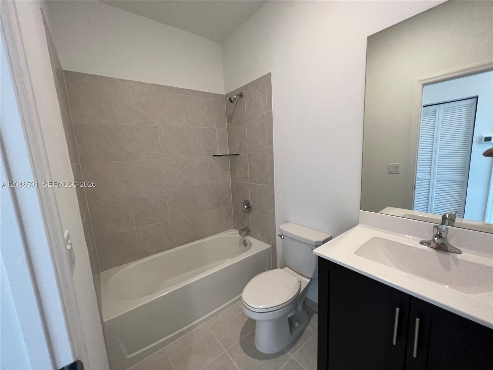 A bathroom features a bathtub with tiled walls, a toilet, and a dark vanity — 1864 SE 27th Rd, Homestead FL 33035, HOMESTEAD, FL
