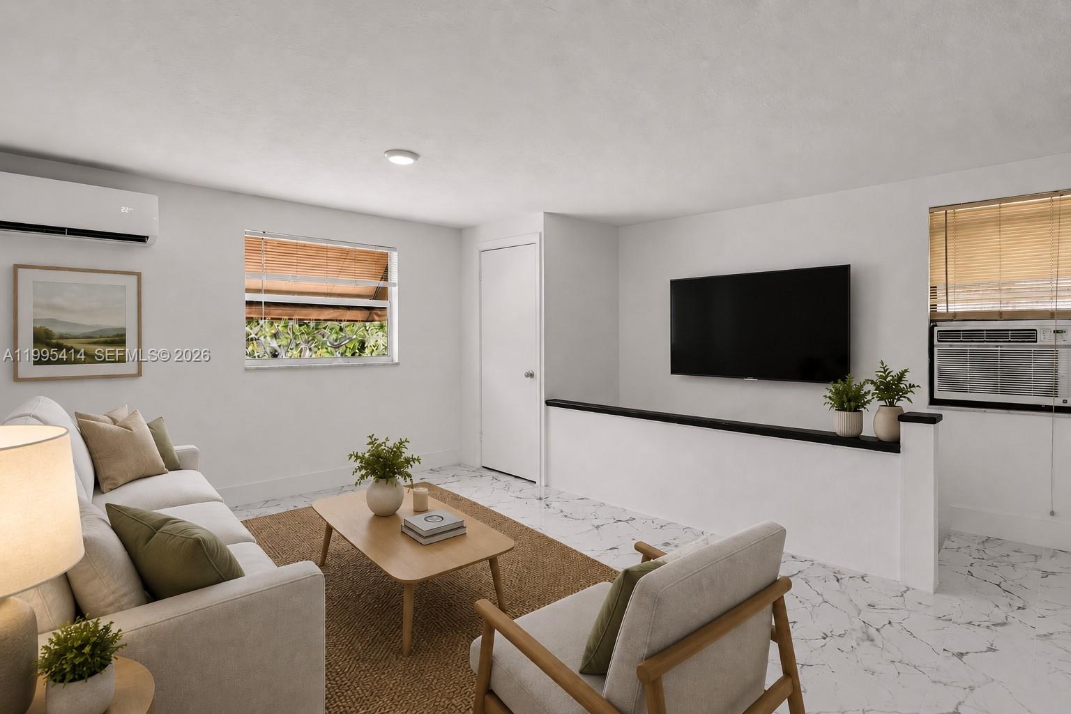 This living room features white walls, marble-patterned tile flooring, a wall-mounted television, and a sofa — 54 NW 62nd St # 1, Miami FL 33150, MIAMI, FL