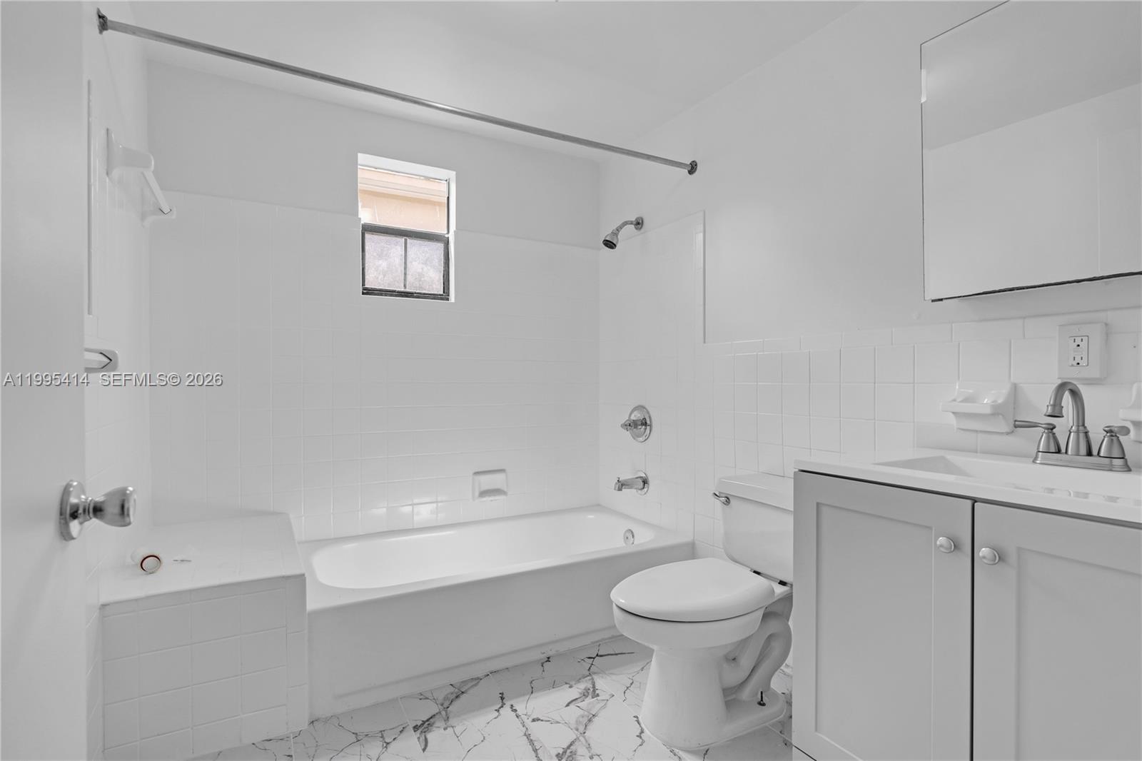 A bathroom features a white tiled tub-shower combination, a toilet, and a gray vanity — 54 NW 62nd St # 1, Miami FL 33150, MIAMI, FL