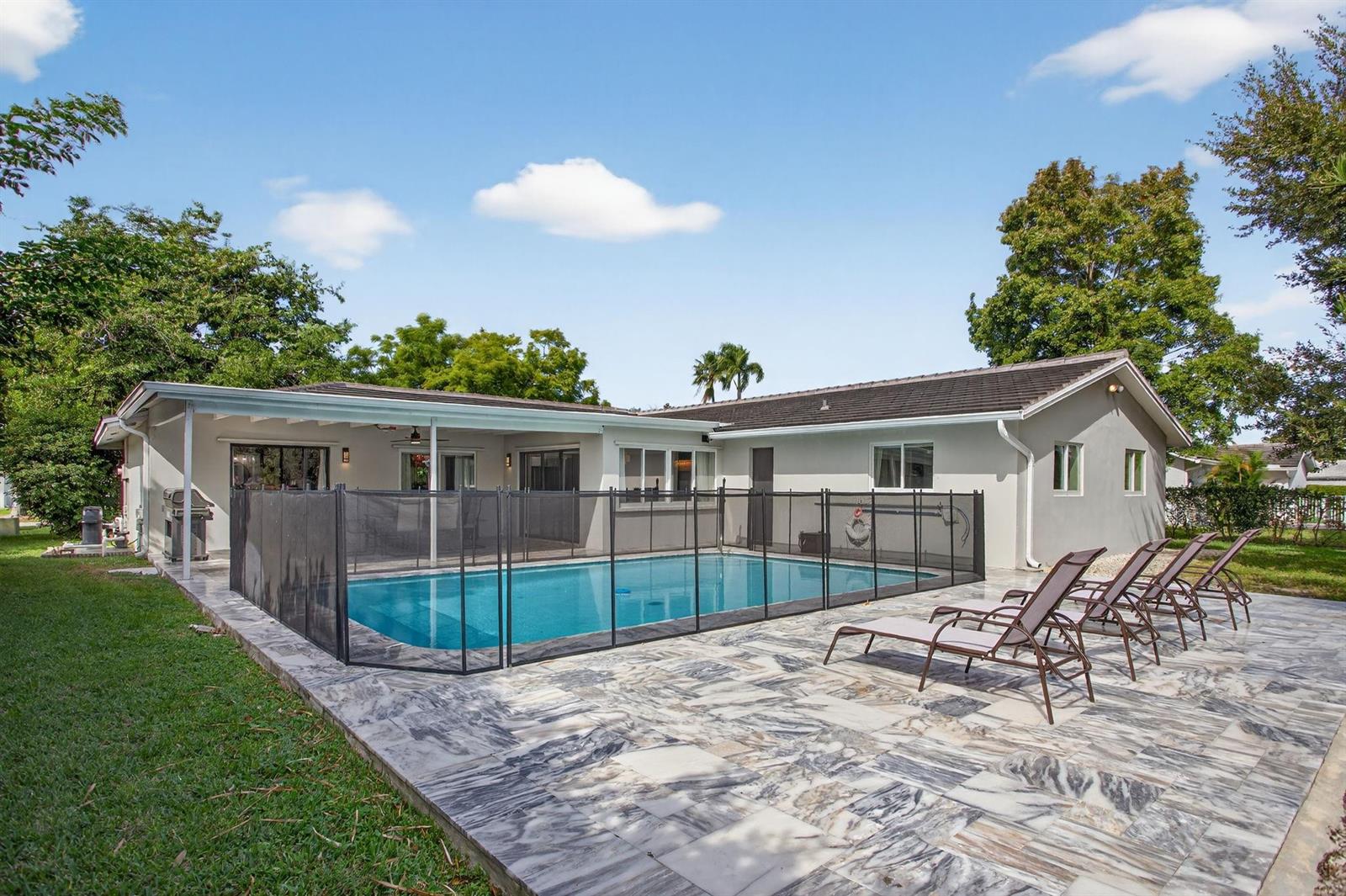 A backyard features a swimming pool with a safety fence and a marble patio — 2421 NW 114th Avenue, Coral Springs FL 33065, CORAL SPRINGS, FL