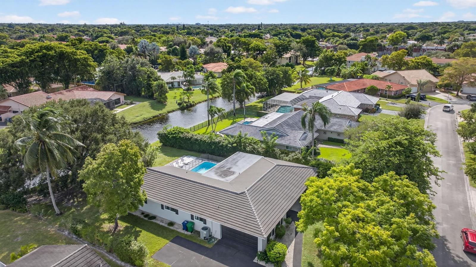 An aerial view of a suburban house with a pool, flat roof, and canal backyard — 2421 NW 114th Avenue, Coral Springs FL 33065, CORAL SPRINGS, FL
