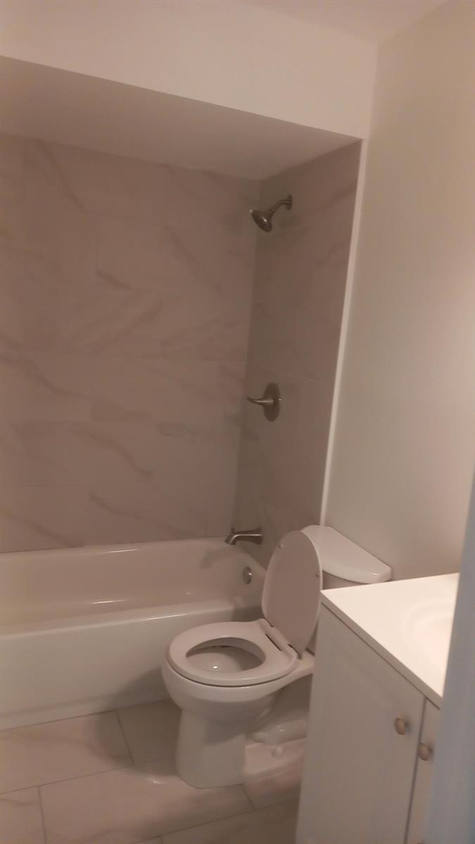 A bathroom featuring a white vanity, a toilet, and a bathtub with tiled walls — 4165 SW 67th Avenue # 208b, Davie FL 33314, DAVIE, FL