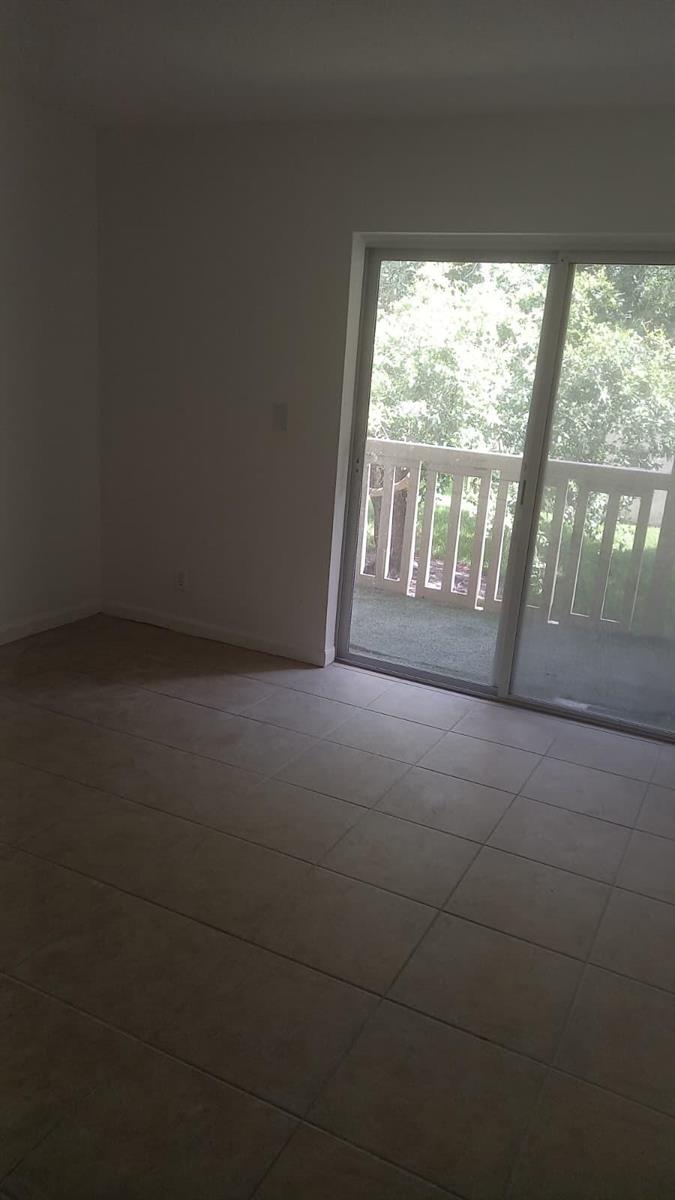 A room with light-colored tile flooring and a sliding glass door leading to a balcony — 4165 SW 67th Avenue # 208b, Davie FL 33314, DAVIE, FL