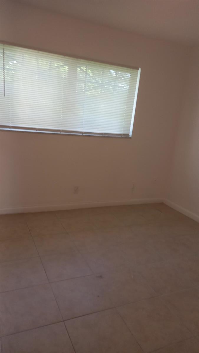 An empty room with light-colored tile flooring and a window covered by horizontal blinds — 4165 SW 67th Avenue # 208b, Davie FL 33314, DAVIE, FL
