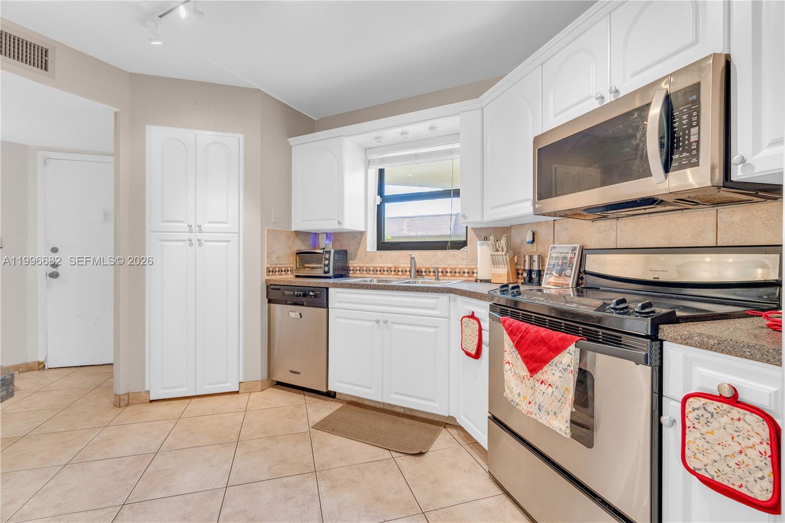 A kitchen features white cabinets, stainless steel appliances, tile flooring, and a window above the sink — 6755 W Broward Blvd # 405, Plantation FL 33317, PLANTATION, FL
