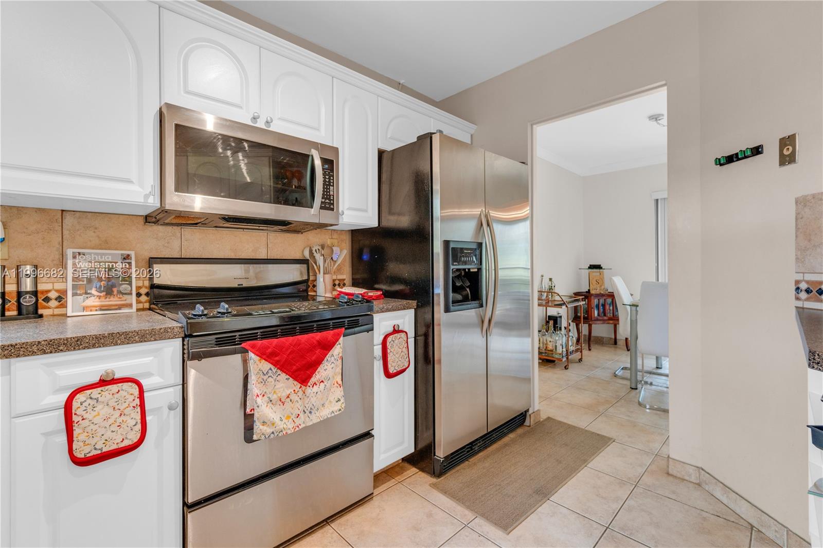 A kitchen features white cabinets, stainless steel appliances, and a tiled floor — 6755 W Broward Blvd # 405, Plantation FL 33317, PLANTATION, FL