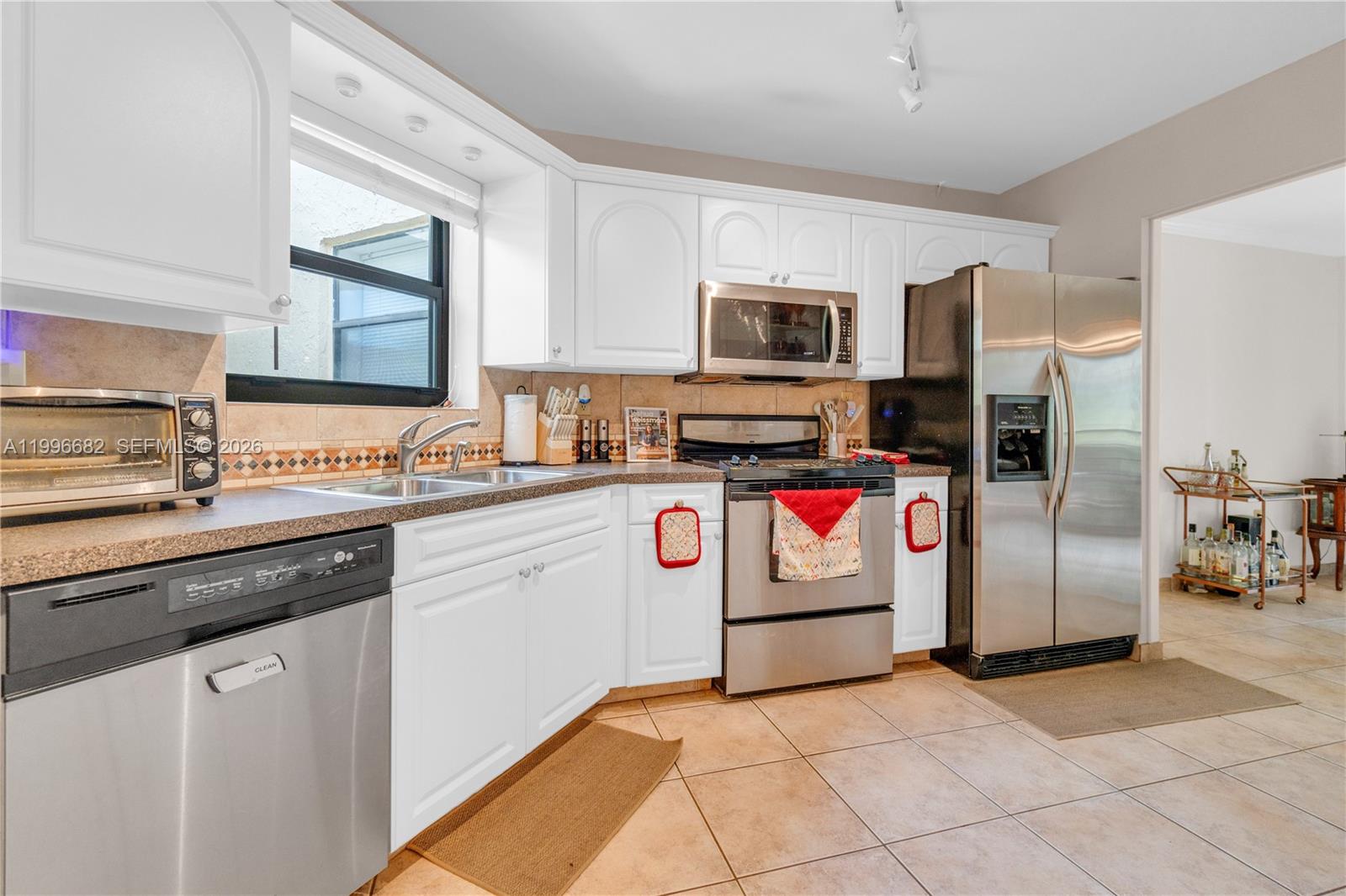 A kitchen features white cabinets, stainless steel appliances, tile flooring, and a tiled backsplash — 6755 W Broward Blvd # 405, Plantation FL 33317, PLANTATION, FL