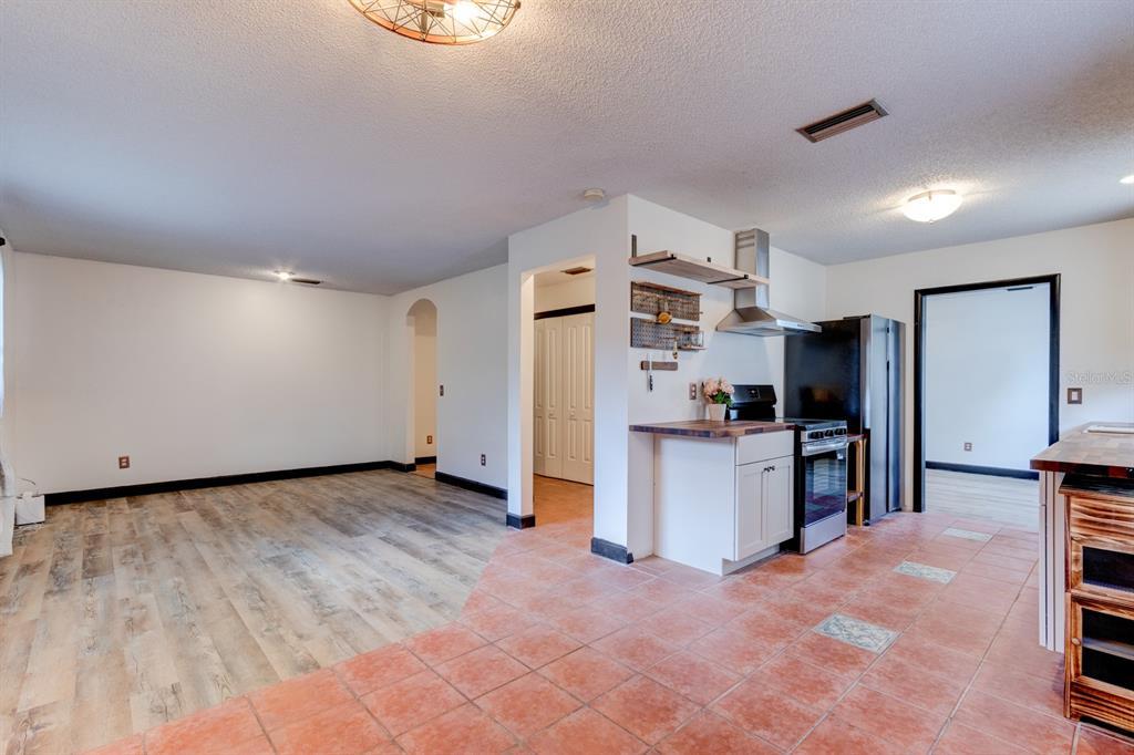 A kitchen with terracotta tile flooring and a living area with wood-look laminate flooring — 119 BIGELOW DRIVE, EDGEWATER, FL