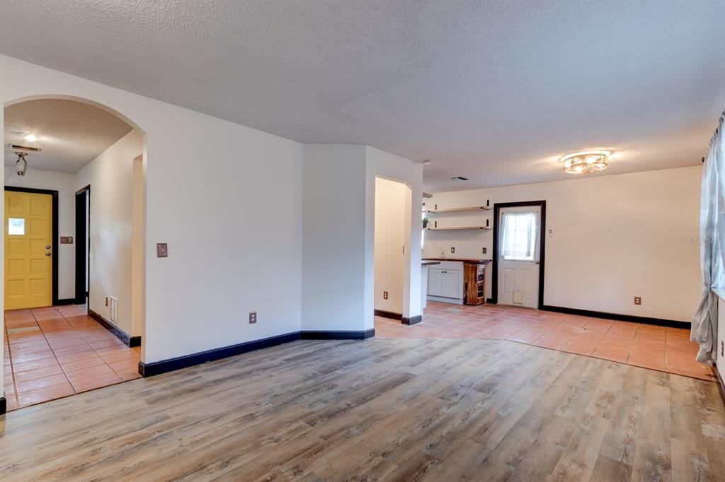 An interior view shows a living area with wood-look flooring and a tiled kitchen space — 119 BIGELOW DRIVE, EDGEWATER, FL