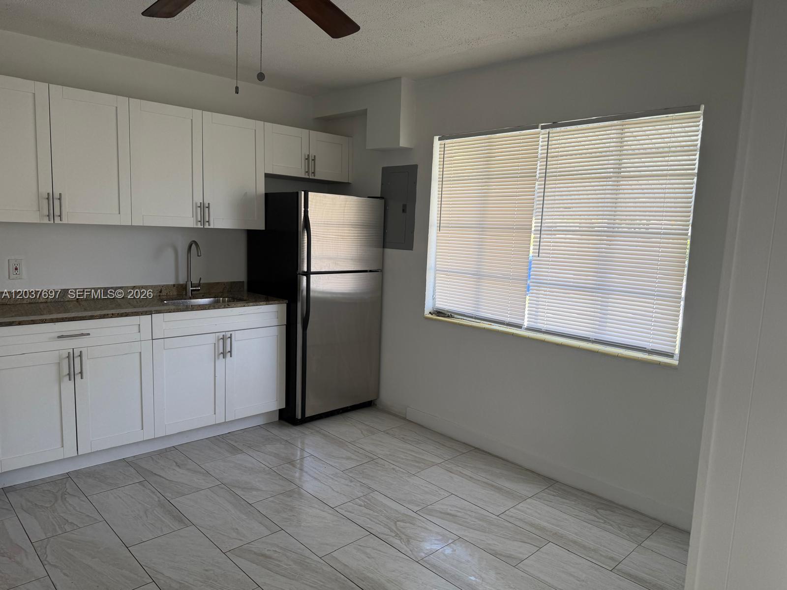 A kitchen features white cabinets, stainless steel appliances, granite countertops, and light-colored tile flooring — 1324 N 58 AVE # 1, Hollywood FL 33021, HOLLYWOOD, FL