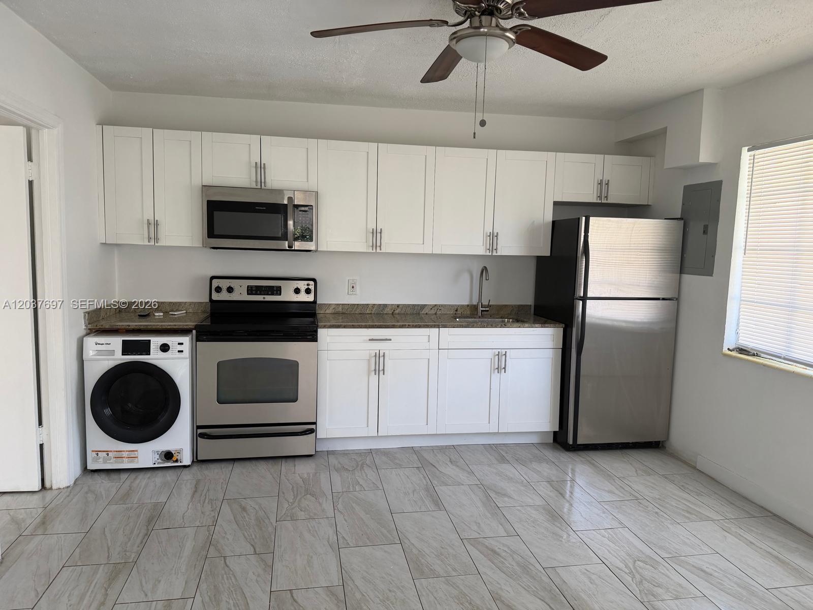 A kitchen features white cabinets, stainless steel appliances, a built-in washer, and light tile flooring — 1324 N 58 AVE # 1, Hollywood FL 33021, HOLLYWOOD, FL
