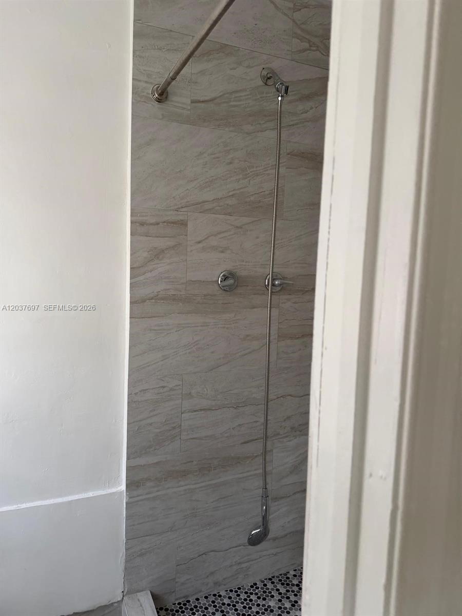 A shower stall features light-colored marble-look wall tiles and a dark mosaic tile floor — 1324 N 58 AVE # 1, Hollywood FL 33021, HOLLYWOOD, FL