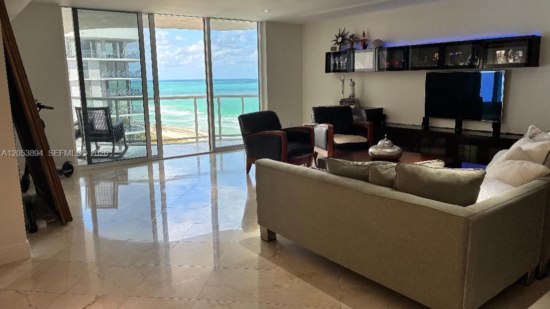 A living room features tile floors, a sofa, armchairs, and a balcony overlooking the ocean — 8855 Collins Ave # 11B, Surfside FL 33154, SURFSIDE, FL