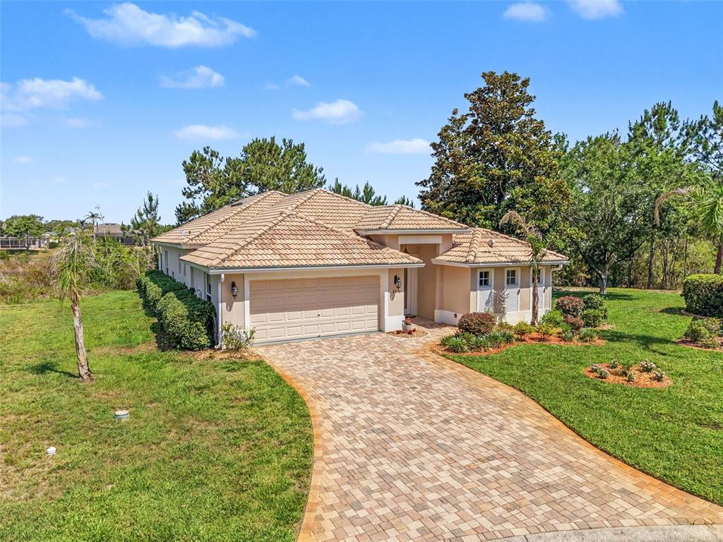 A single-story house with a tiled roof, beige stucco exterior, and a paved driveway — 8910 JERICHO ROAD, WEEKI WACHEE, FL