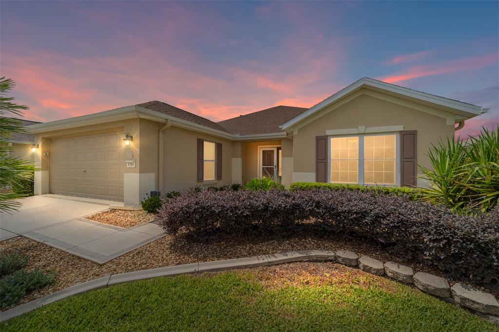 A single-story suburban house with a tan stucco exterior, a garage, and a landscaped yard — 8588 SE 134TH STREET, SUMMERFIELD, FL