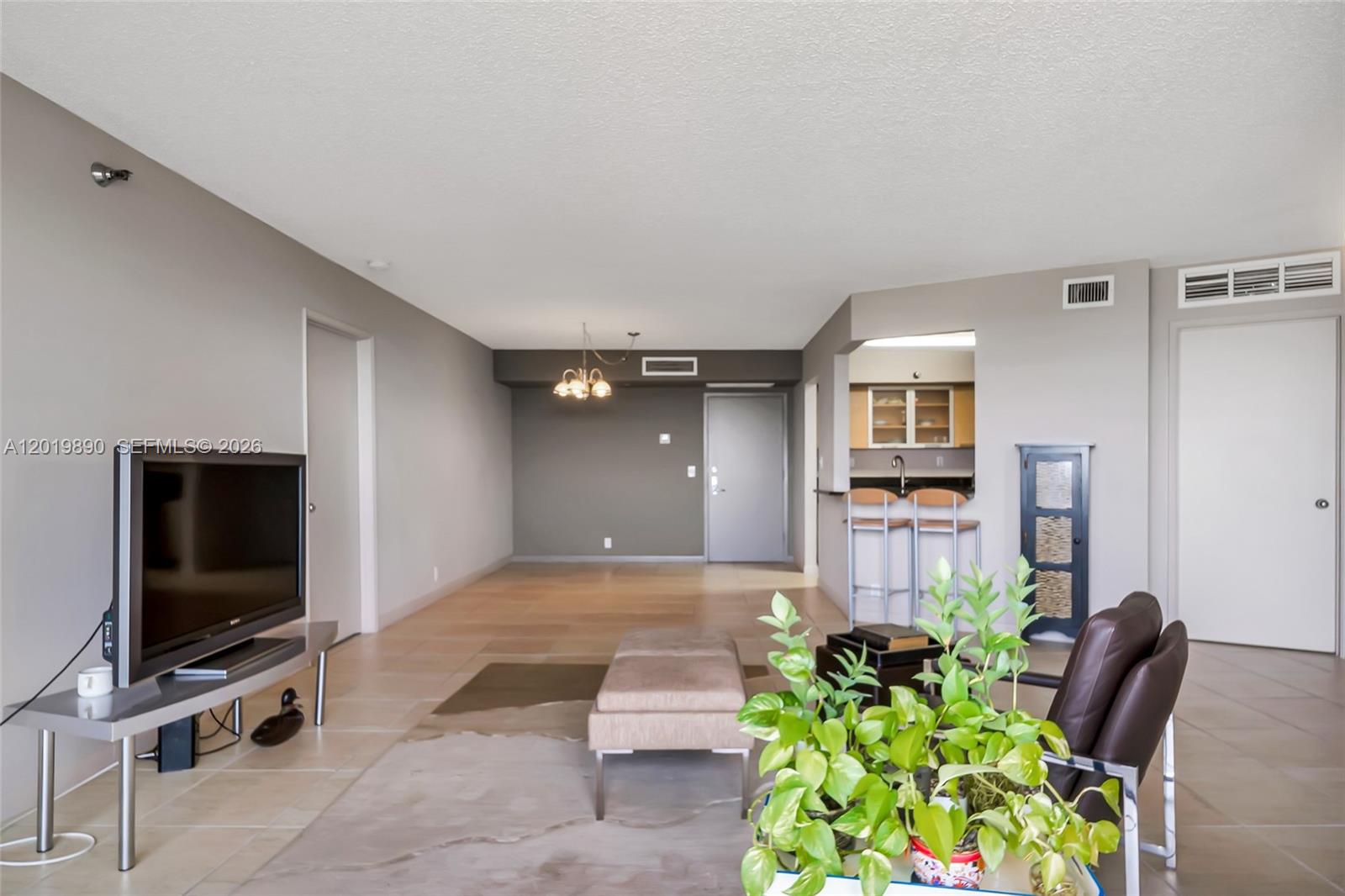 A living room features tile flooring, a television, a dining area, and a kitchen pass-through — 3300 NE 191st St, Aventura FL 33180, AVENTURA, FL