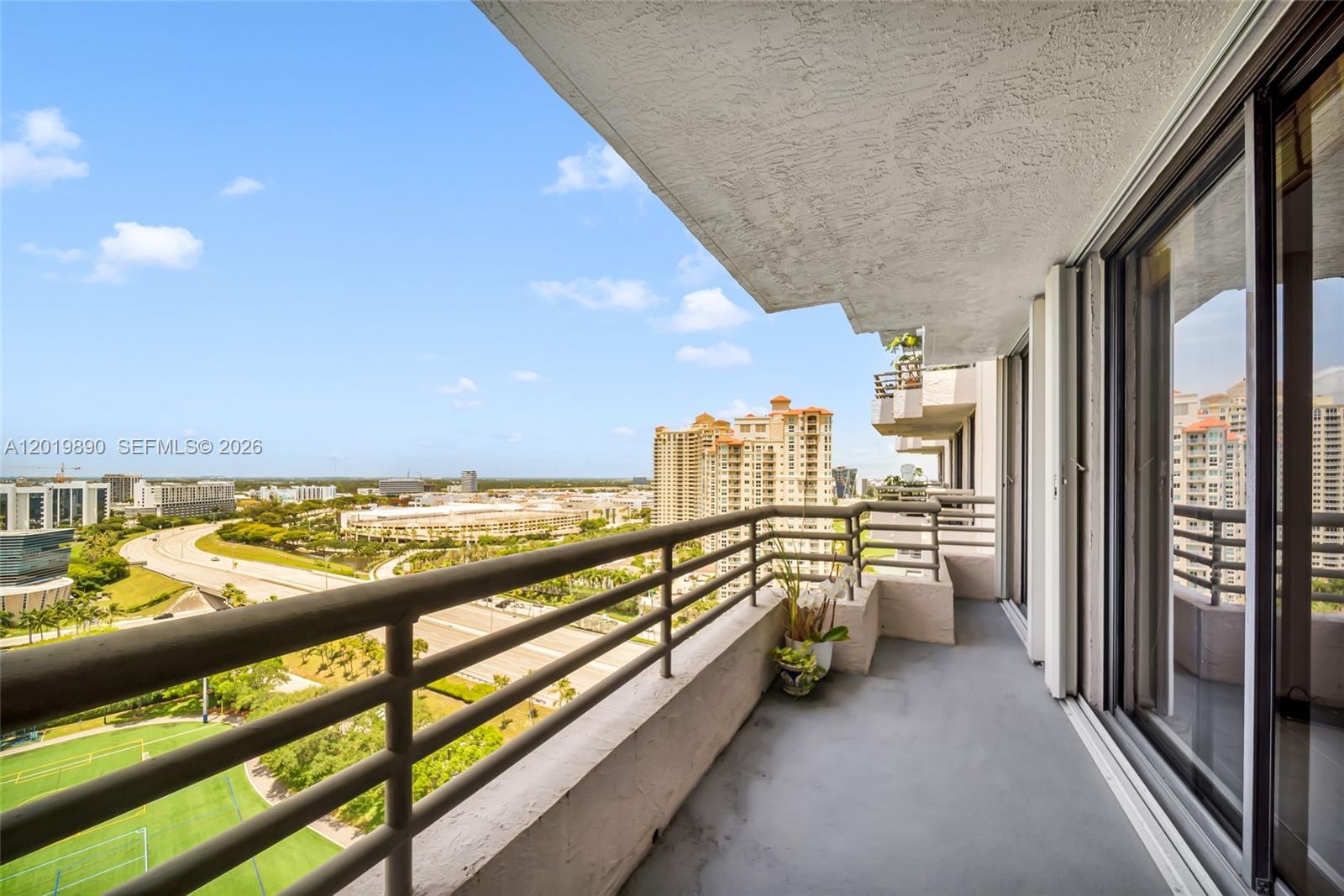 A high-rise balcony overlooks a highway, a green field, and distant city buildings — 3300 NE 191st St, Aventura FL 33180, AVENTURA, FL