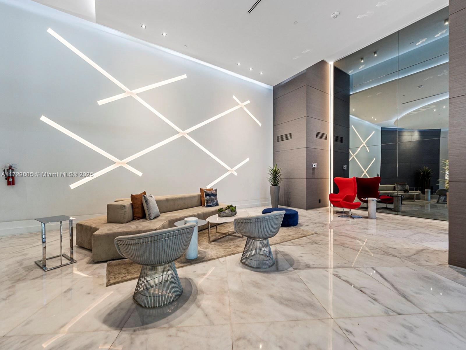 A modern lobby features a large sectional sofa, accent chairs, and geometric wall lighting — 3300 NE 192nd St # 603, Aventura FL 33180, AVENTURA, FL