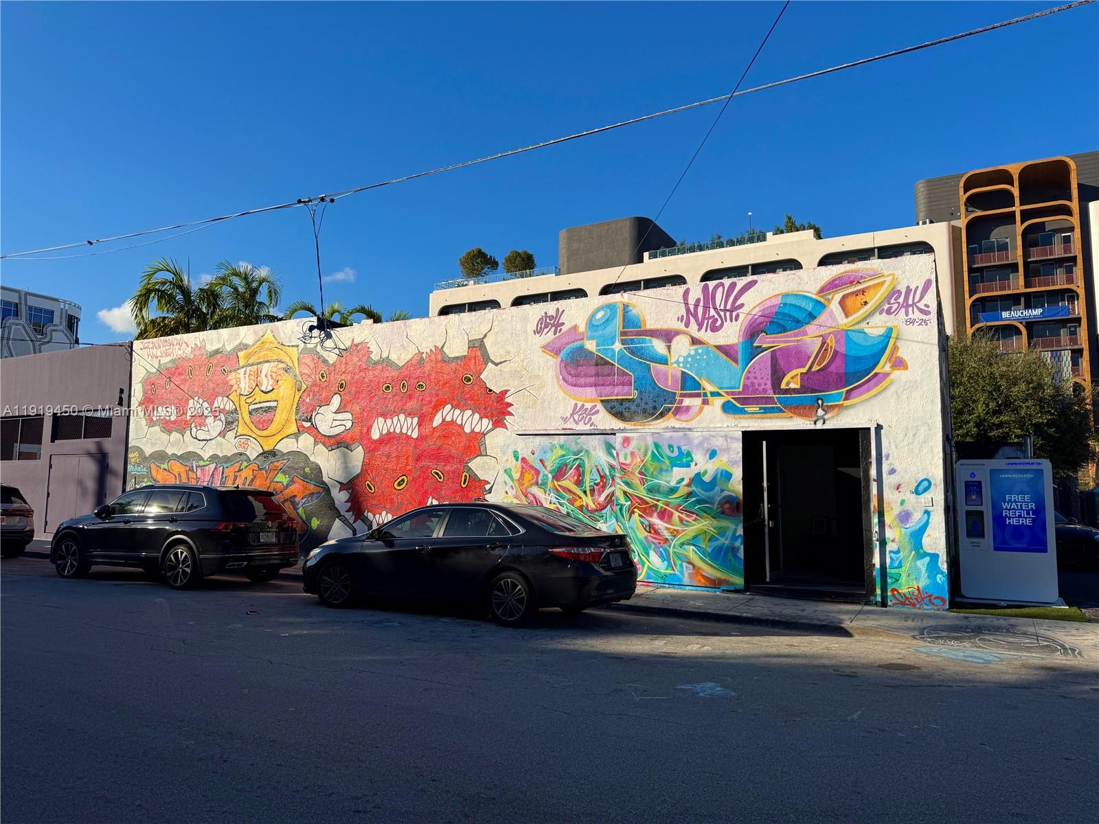 A street-level view of a building exterior featuring colorful graffiti murals and parked cars — 239 NW 26th St, Miami FL 33127, MIAMI, FL