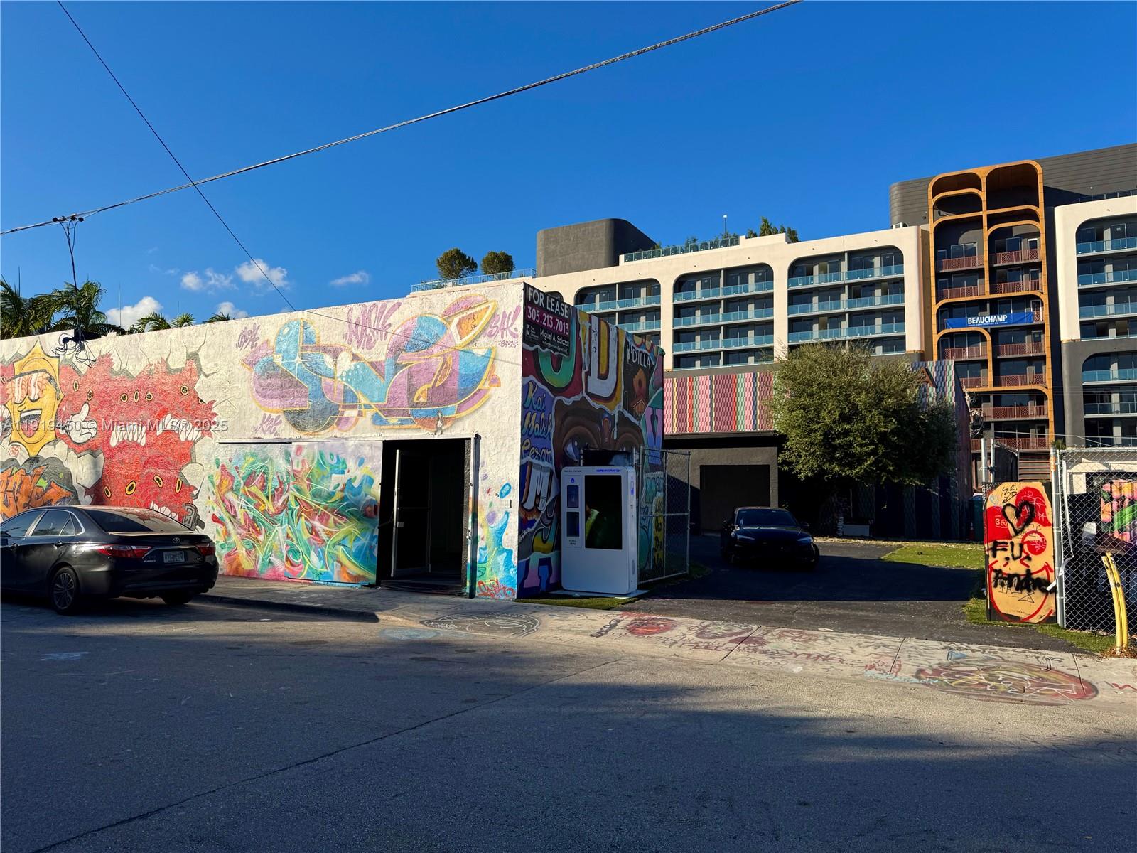 A graffiti-covered building stands next to a modern apartment complex under a clear blue sky — 239 NW 26th St, Miami FL 33127, MIAMI, FL