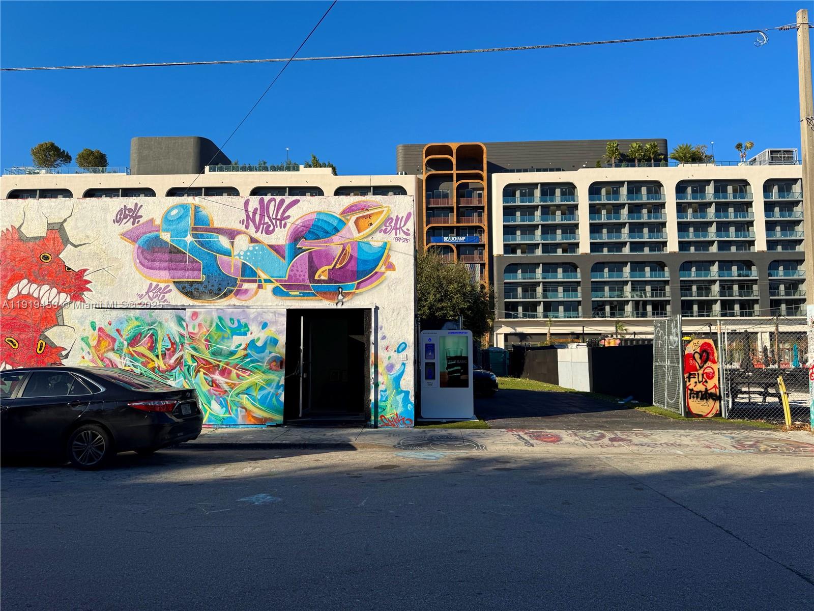 A street-level view shows a white building with colorful graffiti murals next to a modern hotel — 239 NW 26th St, Miami FL 33127, MIAMI, FL