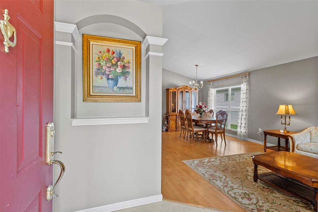 A view from an entryway into a dining room and living area with hardwood floors — 5868 WAR ADMIRAL DRIVE, WESLEY CHAPEL, FL