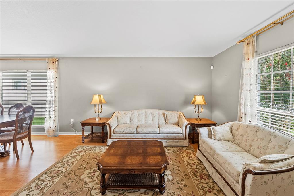 A living room features two floral sofas, a wooden coffee table, and two side lamps — 5868 WAR ADMIRAL DRIVE, WESLEY CHAPEL, FL