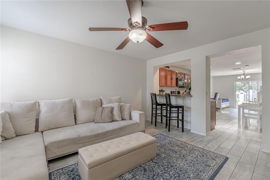 A living room with a beige sectional, ottoman, and a breakfast bar overlooking the kitchen — 5095 DOMINICA DRIVE, KISSIMMEE, FL