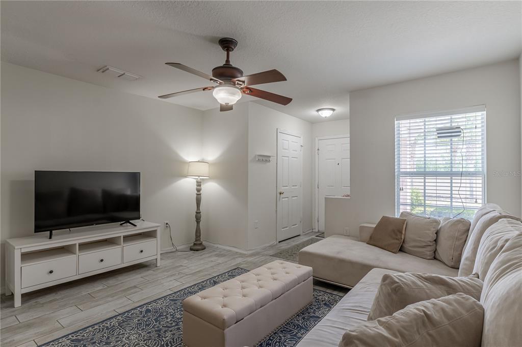 A living room features a white media console, a sectional sofa, and a ceiling fan — 5095 DOMINICA DRIVE, KISSIMMEE, FL