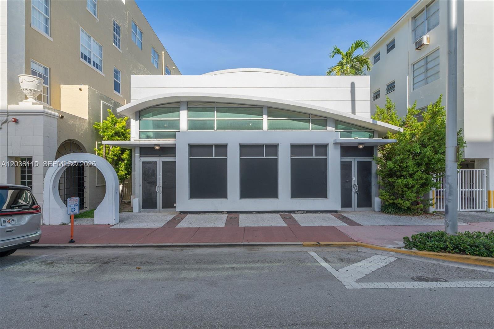 A white, single-story commercial building with a curved roofline sits between two taller apartment buildings — 721 Collins Ave, Miami Beach FL 33139, MIAMI BEACH, FL