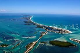 An aerial view shows a narrow barrier island with sandy beaches surrounded by turquoise water — 10425 WINNIPEG STREET, PORT CHARLOTTE, FL