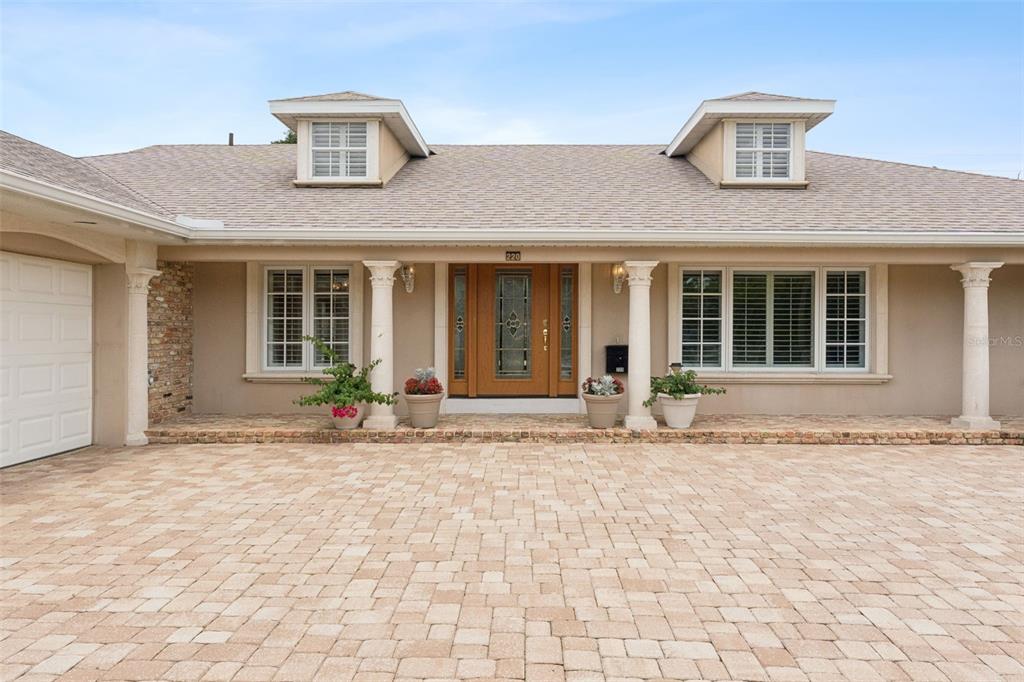 A single-story house features a paved driveway, a covered porch with columns, and two dormers — 220 ROLLINGWOOD TRAIL, ALTAMONTE SPRINGS, FL