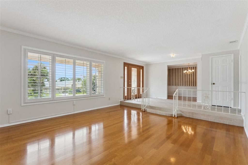 A living room with hardwood floors, a raised entryway, and a large window with shutters — 220 ROLLINGWOOD TRAIL, ALTAMONTE SPRINGS, FL
