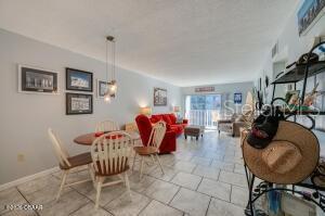 A dining area with a wooden table and chairs sits adjacent to a red sofa — 2711 N HALIFAX AVENUE UNIT 370, DAYTONA BEACH, FL