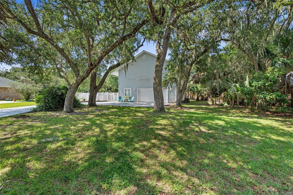 A two-story house with a white garage door sits behind a large, tree-shaded lawn — 26 BEACHSIDE DRIVE, PALM COAST, FL