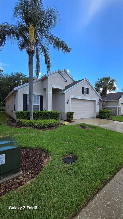 A single-story house with a beige exterior, a two-car garage, and a palm tree — 1604 EAGLE FEATHER DRIVE, KISSIMMEE, FL