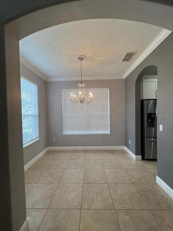 A dining area features tile flooring, a crystal chandelier, and an arched entryway — 1604 EAGLE FEATHER DRIVE, KISSIMMEE, FL