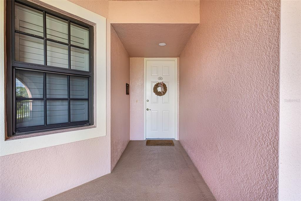 A covered entryway features a white front door with a wreath and a side window — 24367 BALTIC AVENUE UNIT 202, PUNTA GORDA, FL