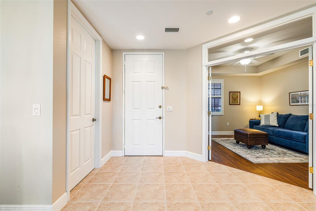 An entryway with tile flooring features a white front door and double glass-paned doors — 24367 BALTIC AVENUE UNIT 202, PUNTA GORDA, FL